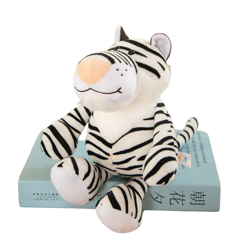 A plush white tiger stuffed plush animal with black stripes and soft orange nose sitting on a light blue book