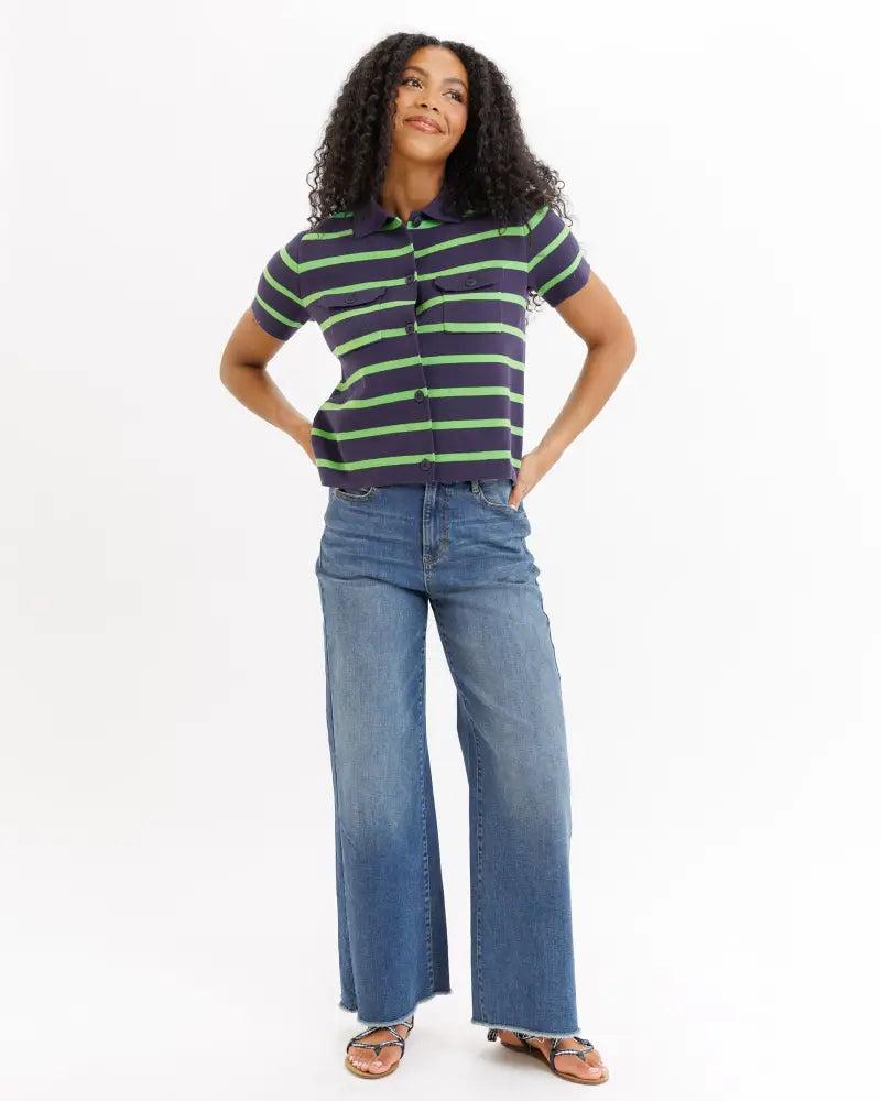 A woman wears a navy and lime green striped cotton short sleeve summer camp cardigan top with chest pockets