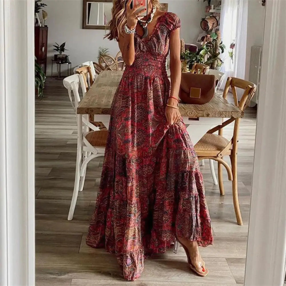 A flowing tiered maxi dress in rich red and burgundy tones featuring an intricate floral paisley v neck pattern
