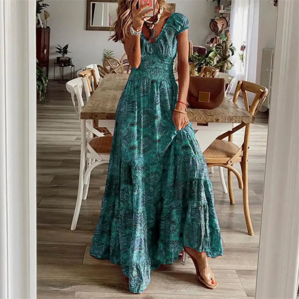 A flowing teal floral paisley v neck tiered maxi dress with an intricate dark green pattern on soft fabric