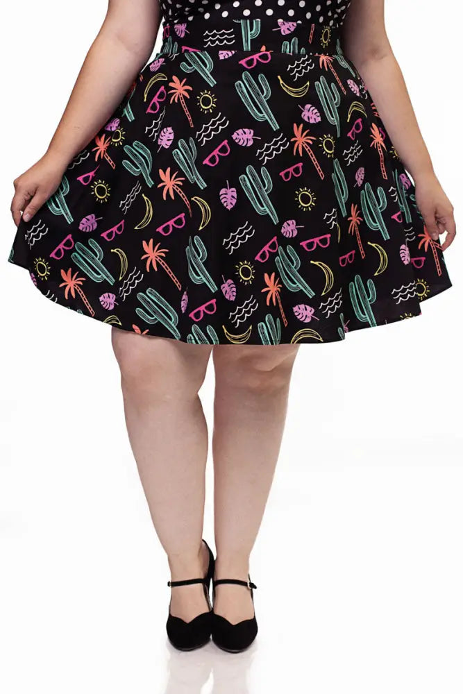 Black plus-size flared skater skirt with neon desert print featuring cacti palm trees sunglasses and bananas