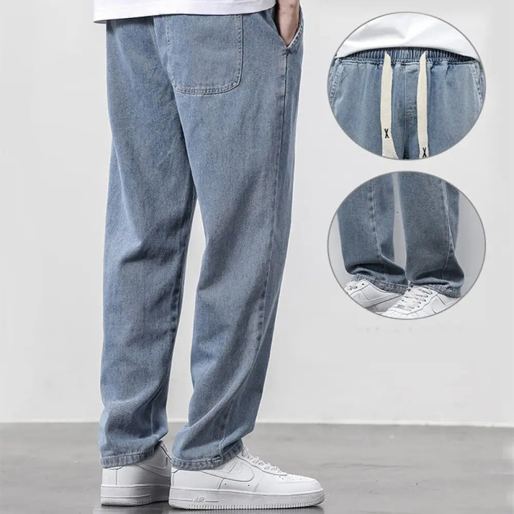 Men’s wide leg light wash denim joggers with elastic waistband and white drawstrings in light-wash denim material