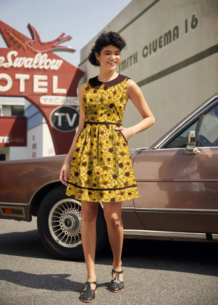 Yellow sunflower print cotton sleeveless dress with black collar belt and pockets in a retro style