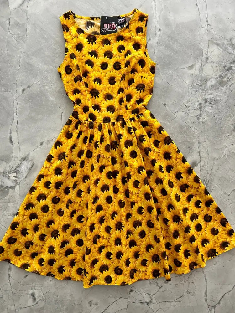 A vibrant yellow vintage sunflower print 1950s cotton midi dress with fitted bodice flared skirt and pockets