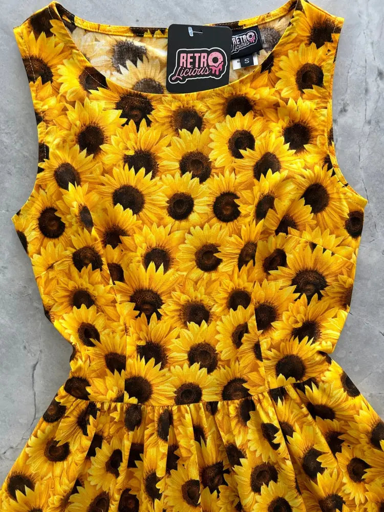 A vibrant yellow vintage sunflower print 1950s cotton midi dress with fitted bodice flared skirt and pockets