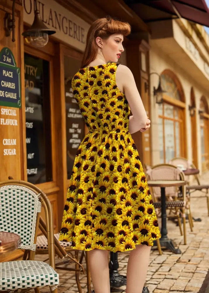 A vibrant yellow vintage sunflower print 1950s cotton midi sleeveless dress with fitted waist and flared skirt with pockets