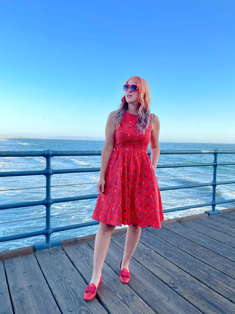 A vibrant red floral sunglasses print sleeveless cotton a line dress with a fitted bodice and flared skirt