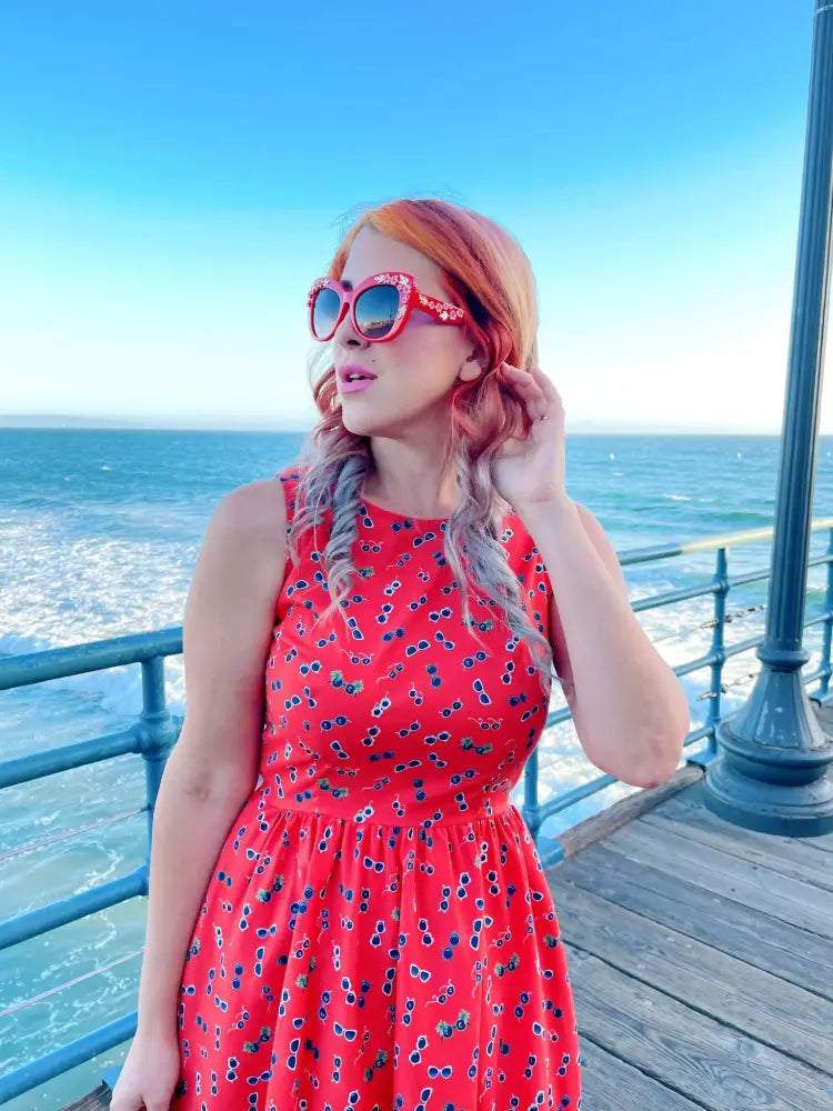 A vibrant red sleeveless cotton a line dress with a playful dark sunglasses print perfect for summer wear