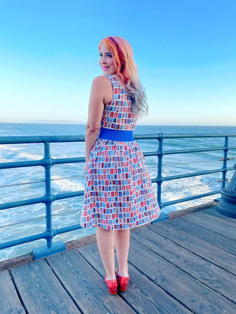 A woman wears a sunny days vintage house print fit and flare sleeveless dress with red and blue rectangles on white