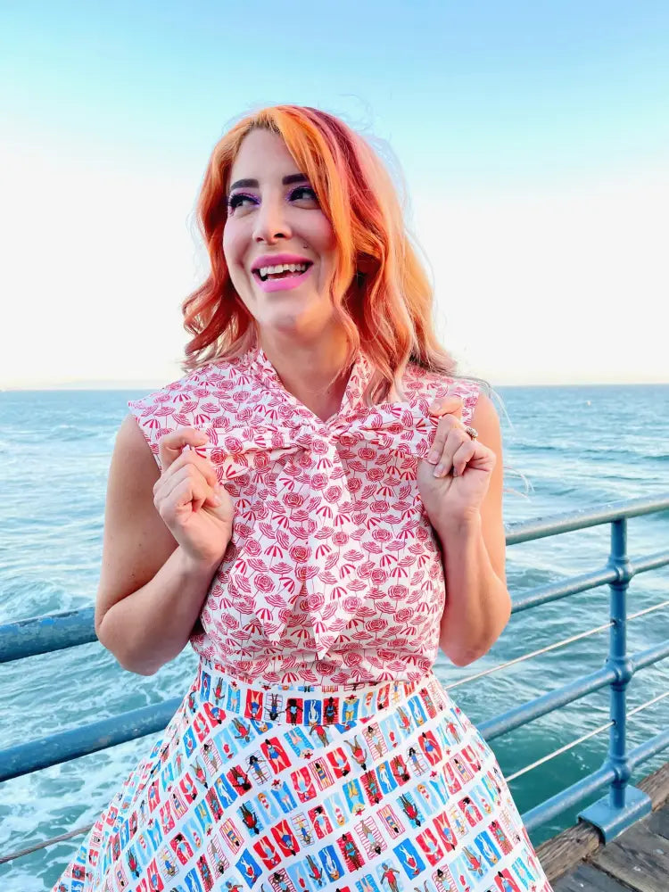 A woman wears a vintage-style pink and white patterned top with ruffled sleeves and a Sunny Days Vintage Phone Print skater skirt