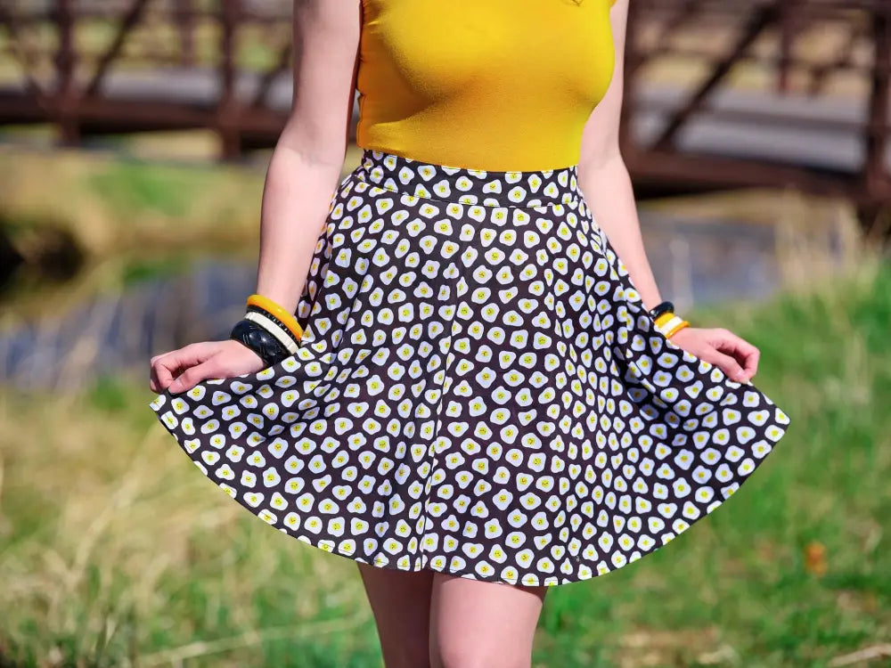 A black a-line sunny side up polka dot skater skirt with a playful white and yellow daisy pattern
