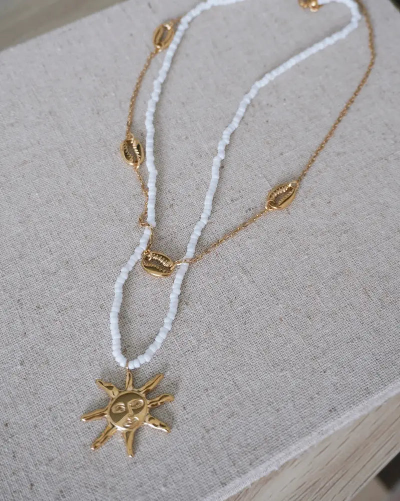 Sunseeker white seed bead necklace with gold-toned sun pendant and shell-shaped charms on beaded strands