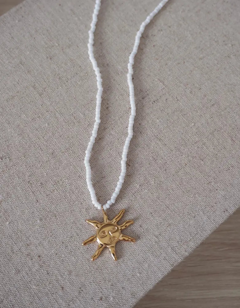 Sunseeker white seed bead necklace featuring a delicate gold sun pendant with a smiling face and radiating rays