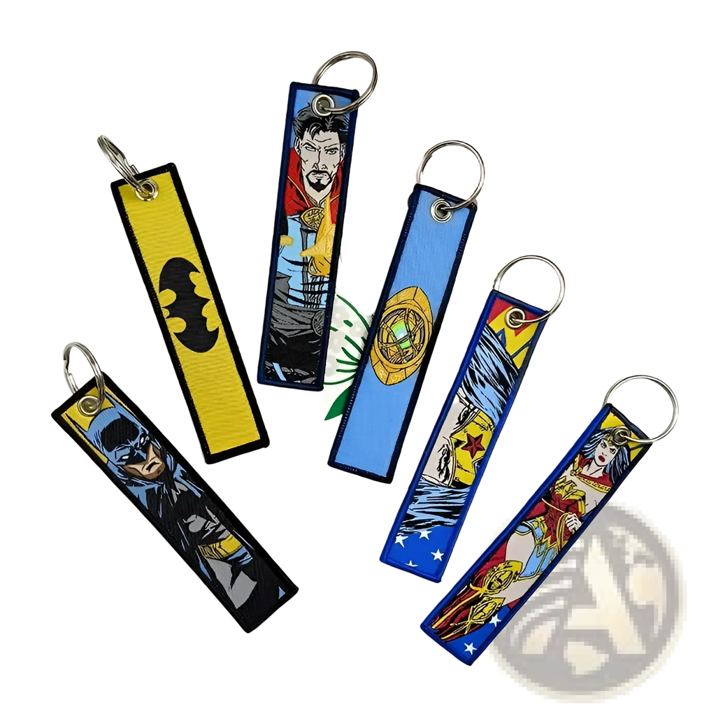 A set of colorful embroidered superhero keychains on fabric tags with metal rings featuring batman and others
