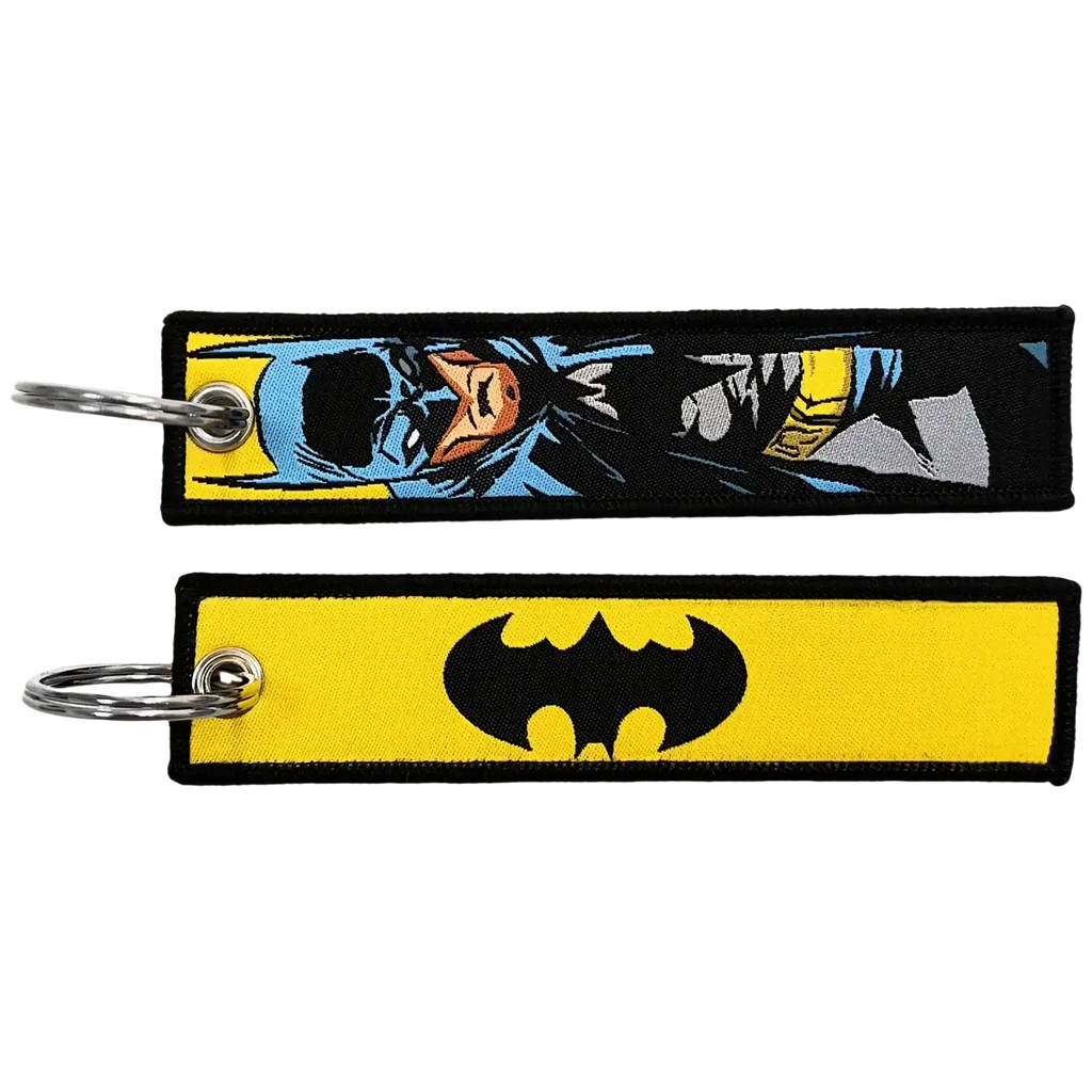 Two superhero embroidered keychains featuring a blue and yellow comic-style batman design and a black bat symbol on yellow fabric