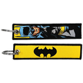 Two superhero embroidered keychains featuring a blue and yellow comic-style batman design and a black bat symbol on yellow fabric