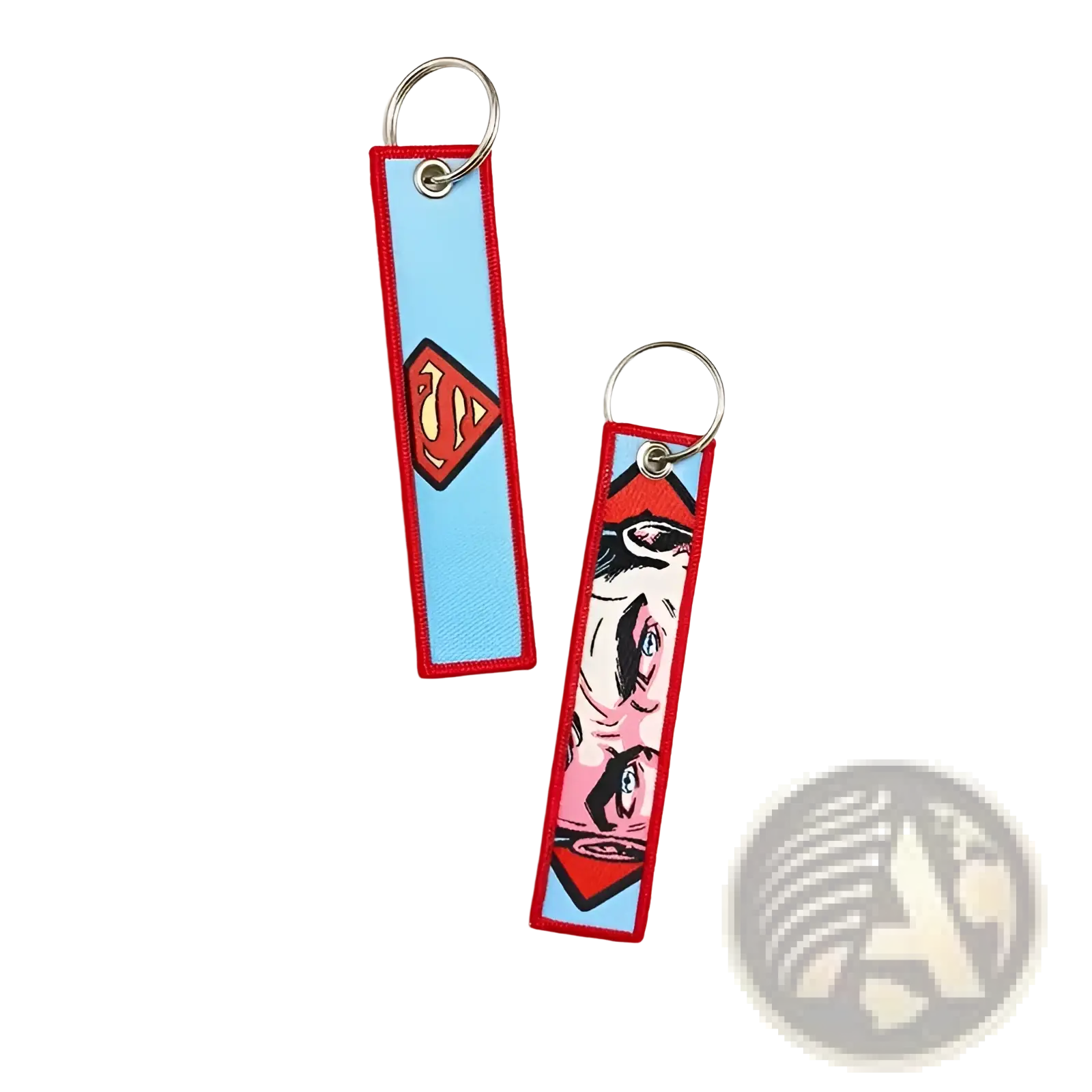Two embroidered superhero keychains featuring a red and yellow Superman logo and a pink comic book face on light blue fabric