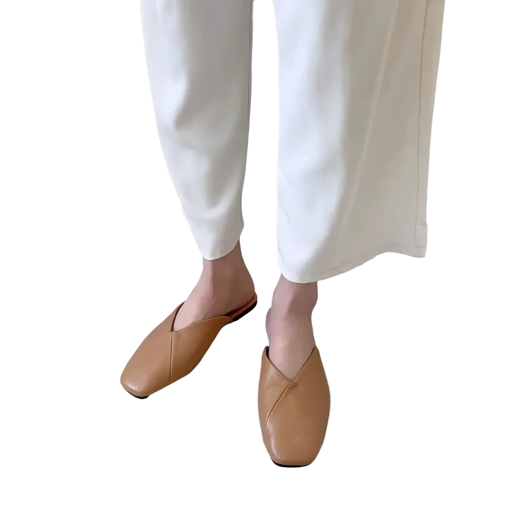 Tan leather square toe mule flat slippers with minimalist design and smooth tan leather upper visible from front angle