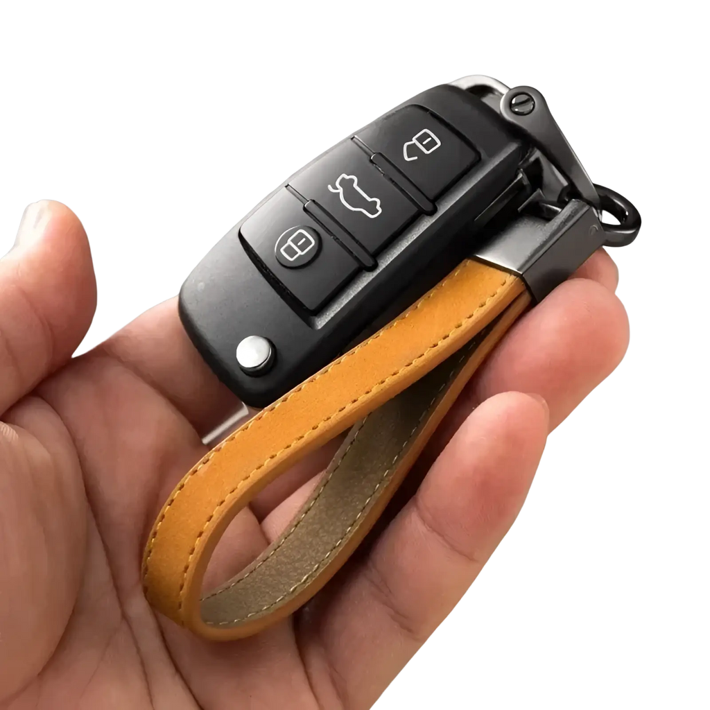 A sleek black audi key fob attached to a tan suede leather car keychain ring with a leather strap