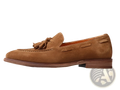 Tan suede tassel loafers with stitched leather accents and a stitched rubber sole for stylish comfort