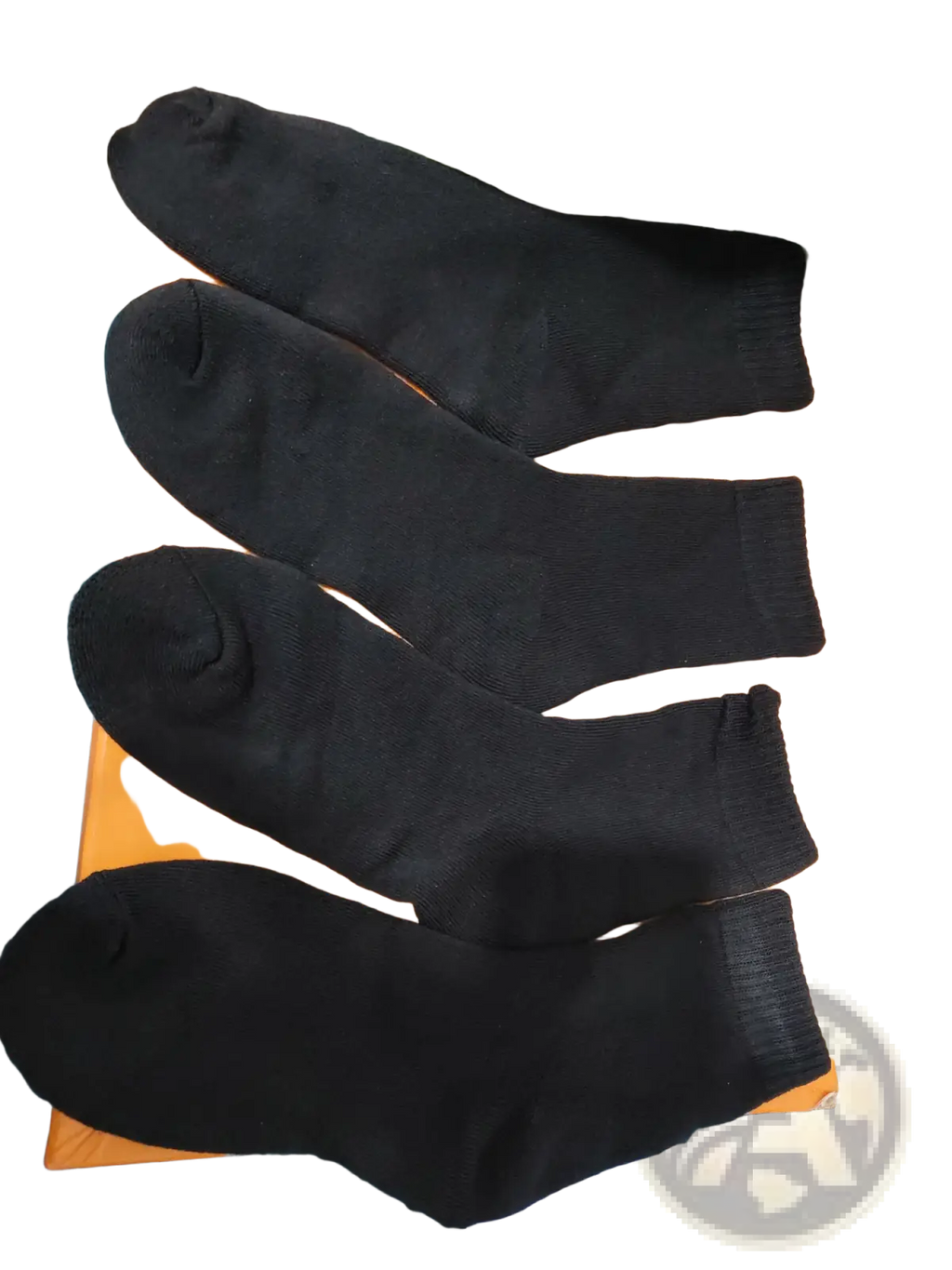 Four black thermal winter socks made of warm fabric neatly arranged on an orange surface for cold protection