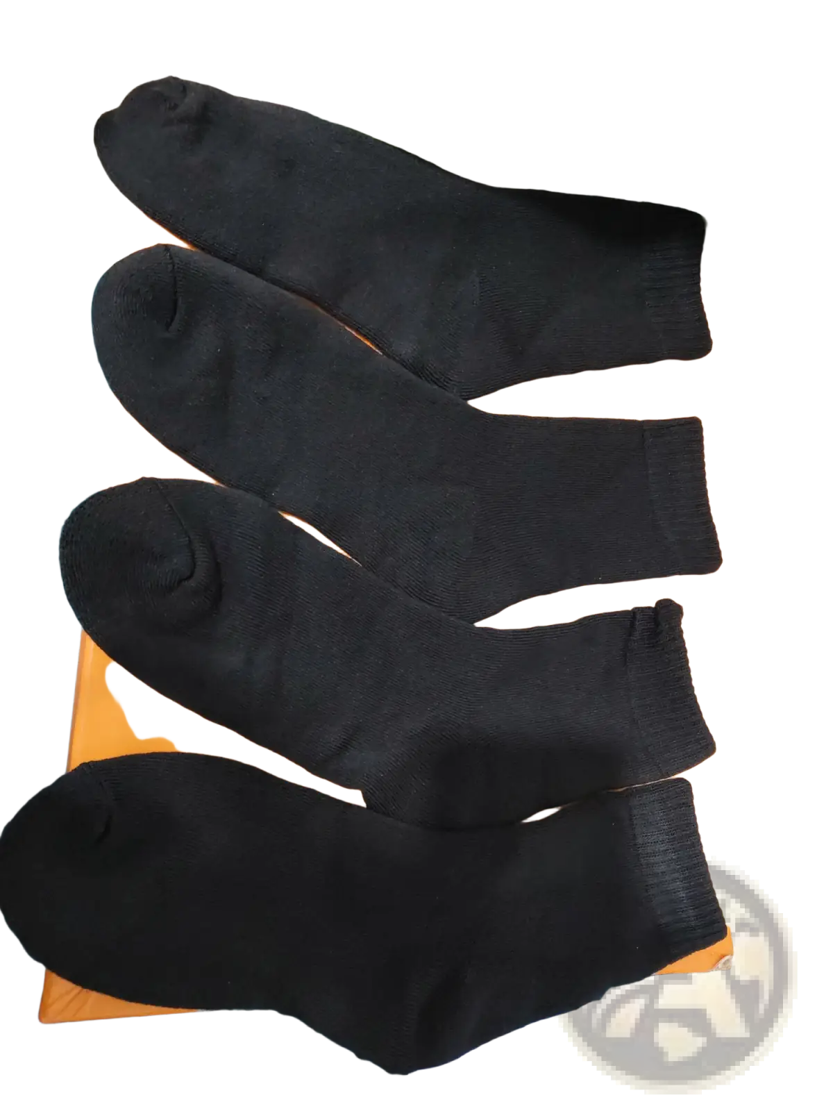 Four black thermal winter socks made of warm fabric neatly arranged on an orange surface for cold protection