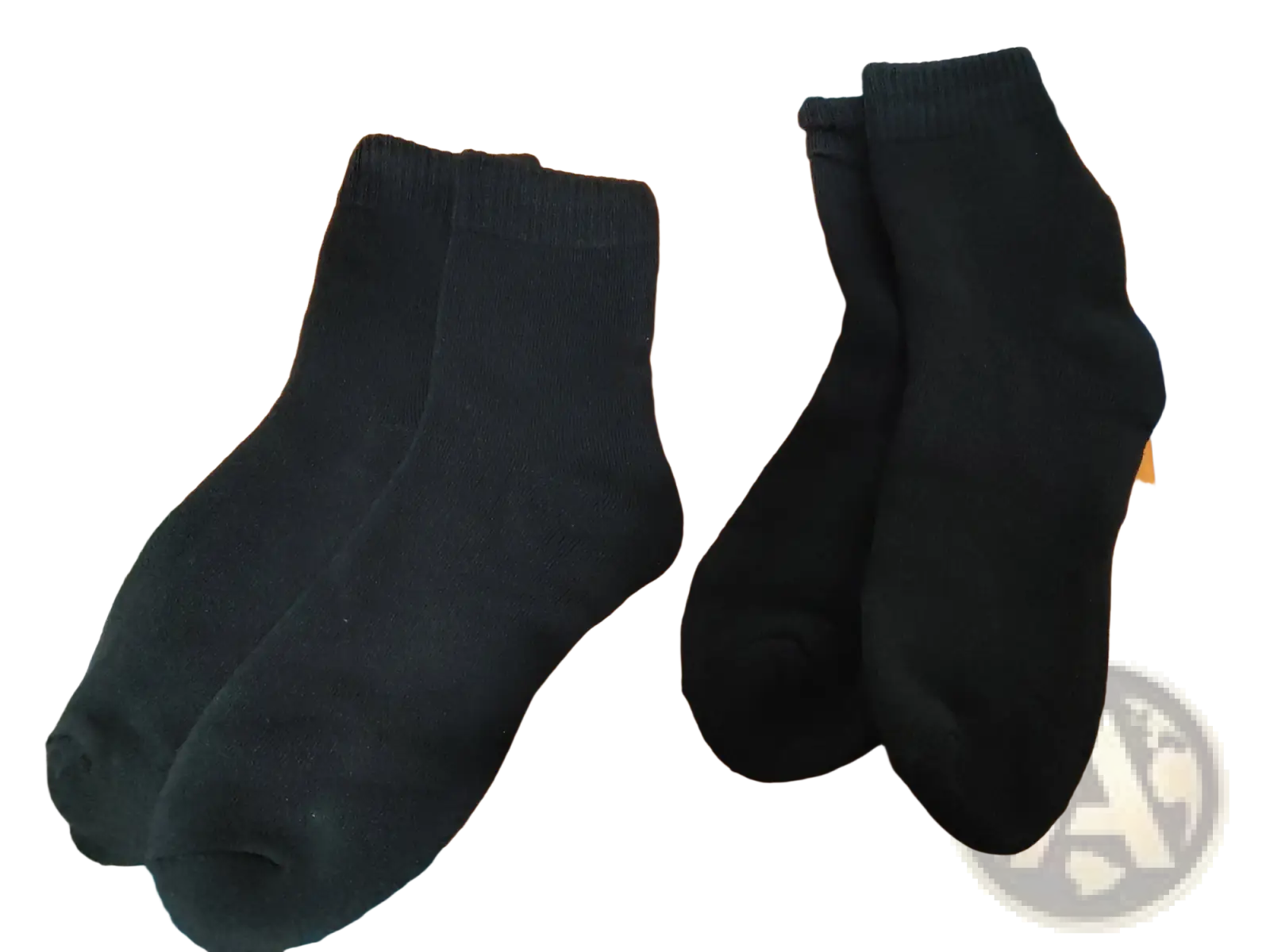 A pair of black thermal winter socks made of plain-knit fabric for unisex cold protection on an orange surface