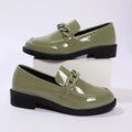 Olive green patent leather loafers with a chunky black sole and decorative chain-link strap across the toe