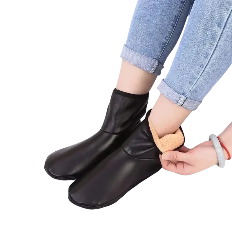 Black faux leather ankle boots with plush tan lining paired with thick fleece middle tube winter socks for warmth