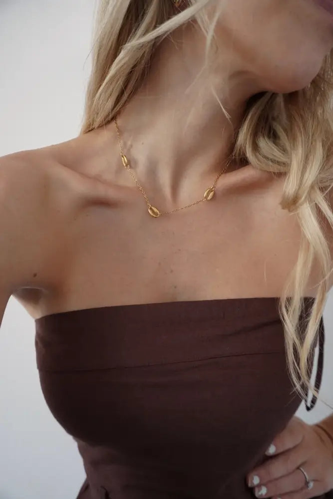 Gold chain necklace with three small oval-shaped gold puka shell pendants in tides gold puka shell pendant necklace