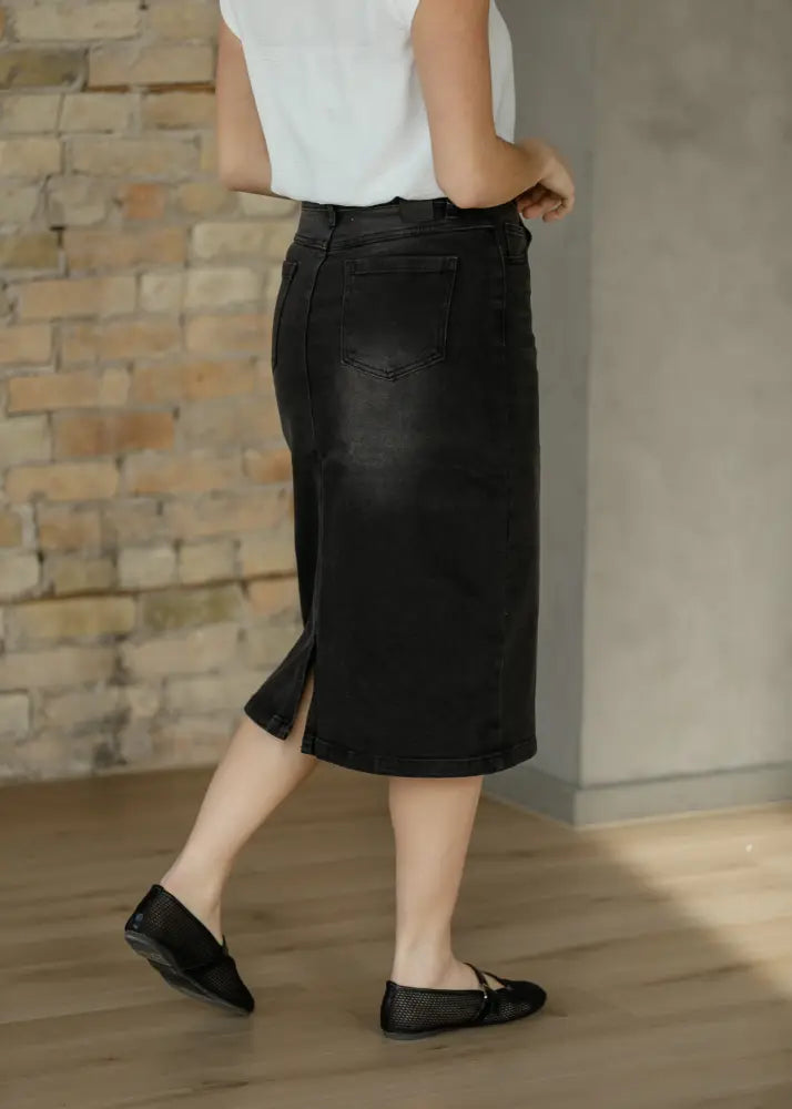 Black denim midi skirt with a side slit and classic back pockets shown from the back in the Tiffany collection