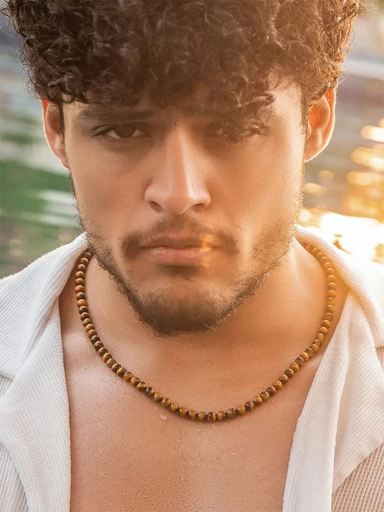 A tiger eye beaded stainless steel necklace with earthy-toned wooden beads and toggle clasp worn around the neck