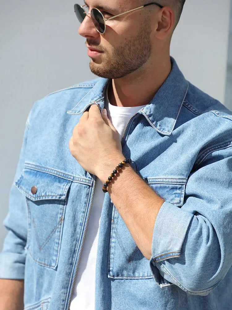 A dark brown tulum tiger eye and black onyx adjustable round-beaded bracelet worn on a mans wrist