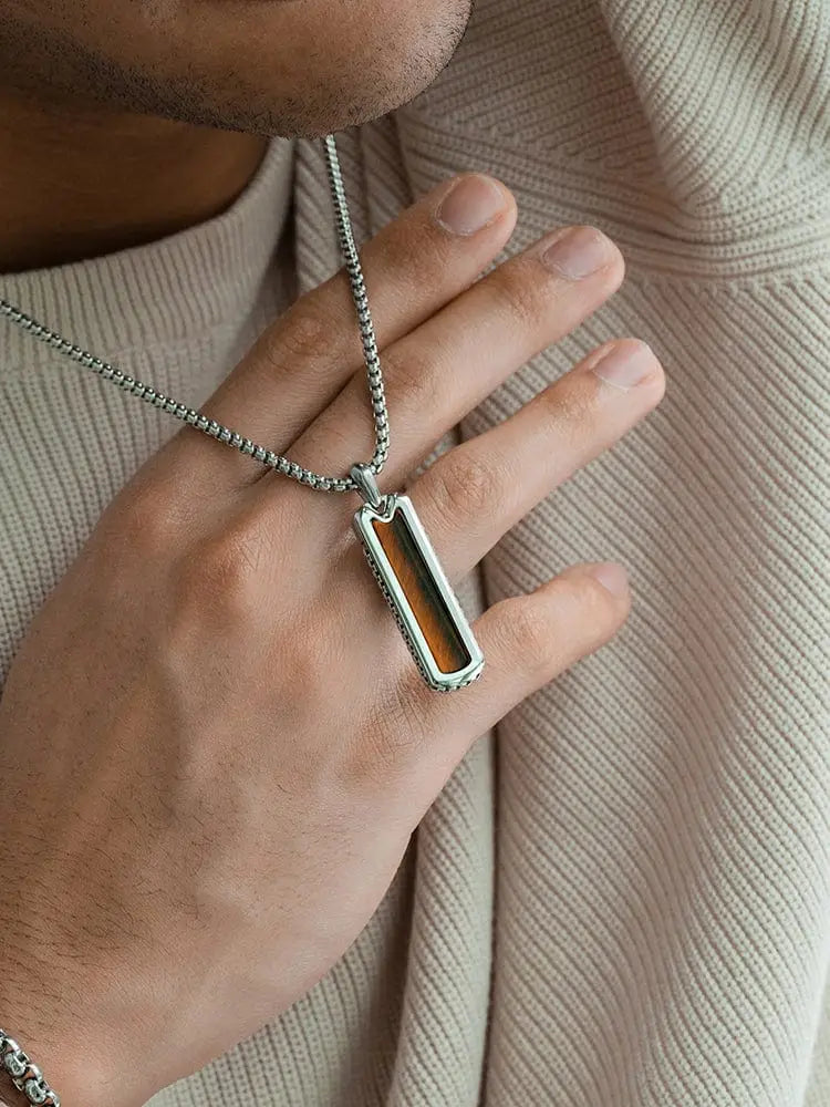 Silver-toned stainless steel rectangular pendant necklace with central amber-colored tiger eye inlay on matching chain