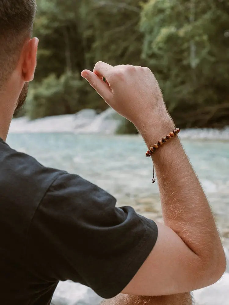 Adjustable bali brown and black tiger eye beaded bracelet in stainless steel worn on a man’s wrist
