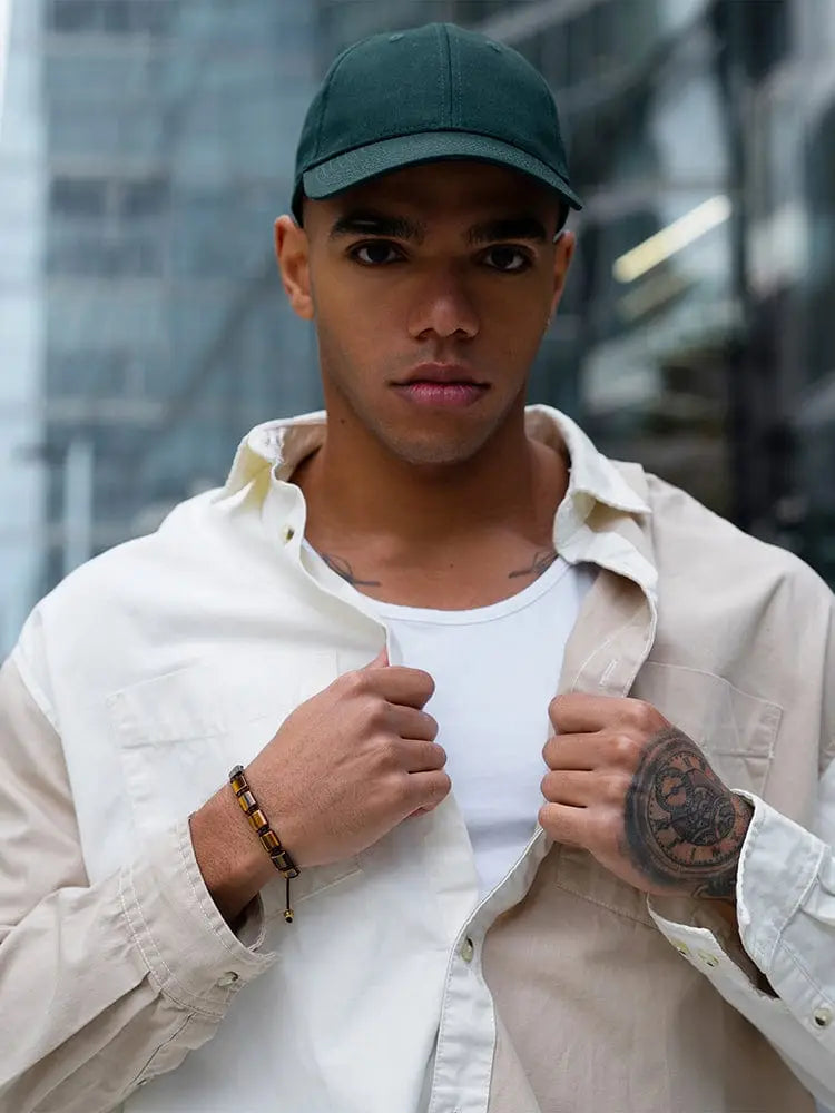 Dark green baseball cap shown from the back paired with havana tiger eye beaded bracelet with gold accents