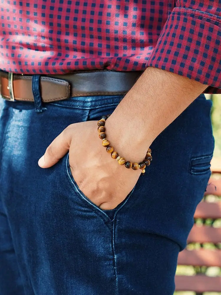 A brown tiger eye beaded bracelet with gold accents worn on a wrist from Mykonos collection
