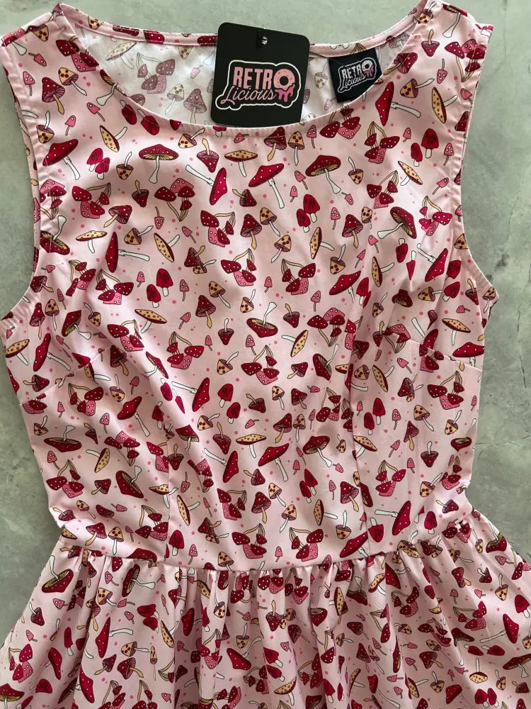 A pink sleeveless 1950s cotton A-line dress with red and brown mushroom print and retro liquors brand tag