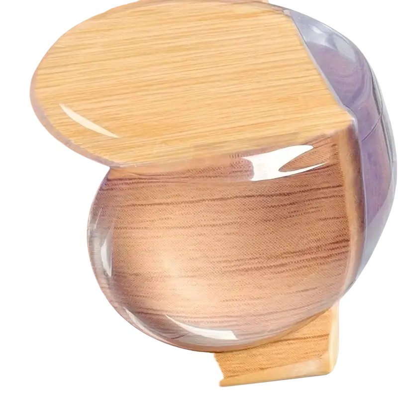 Transparent furniture corner protector guards with clear rounded glossy finish adhered to wooden surface edges