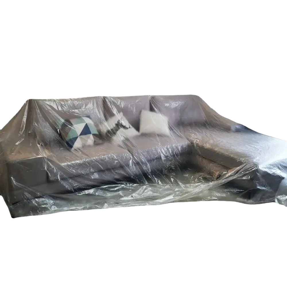 Gray sectional sofa wrapped in transparent plastic furniture dust cover film protecting from dust and dirt