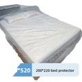 White plastic bed protector with textured surface and reinforced edges covering mattress and pillows for dust protection