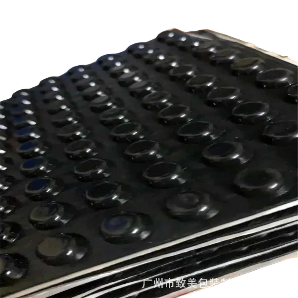 Black rubber foot pads with glossy finish arranged on stacked trays for transparent silicone furniture bumpers and pads