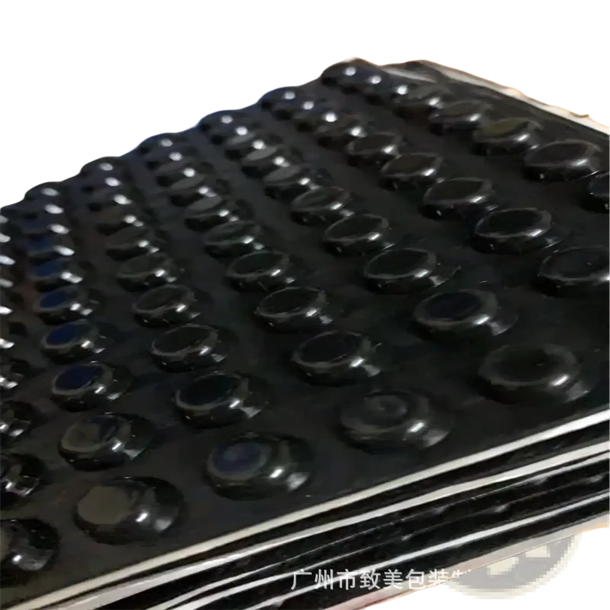 Black rubber foot pads with glossy finish arranged on stacked trays for transparent silicone furniture bumpers and pads