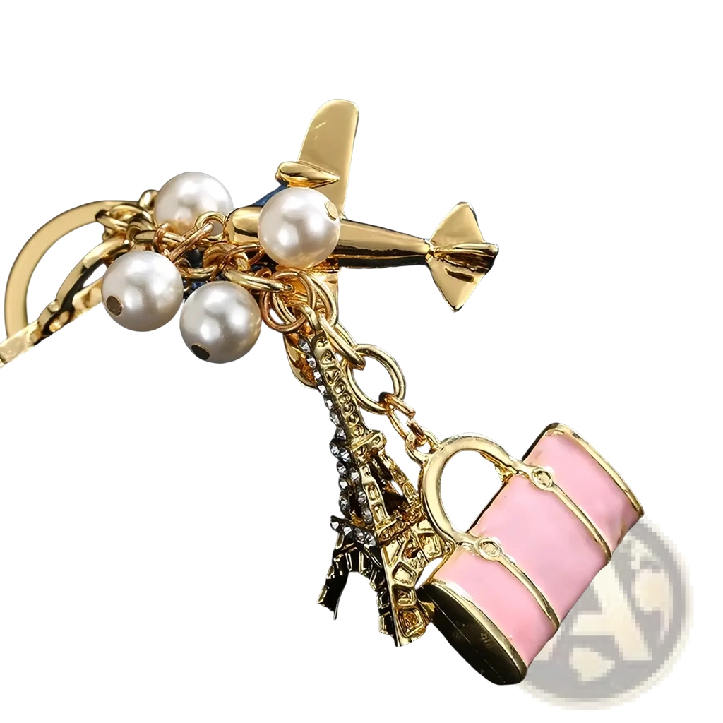 Gold-toned travel keychain with faux pearls mini airplane eiffel tower crystals and pink enamel handbag charm