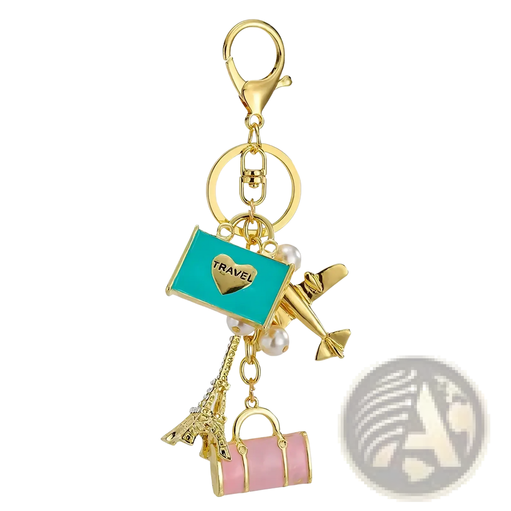 Gold-toned travel keychain featuring turquoise enamel tag with heart, airplane charm, pearl accents, eiffel tower, and suitcase charms