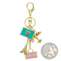 Gold-toned travel keychain featuring turquoise enamel tag with heart, airplane charm, pearl accents, eiffel tower, and suitcase charms