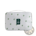 White cactus-patterned travel makeup bag hanging toiletry organizer with green travel label featuring airplane icon
