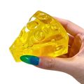 A translucent yellow mini triangle cheese fidget toy with circular holes for soft stress relief squeeze use