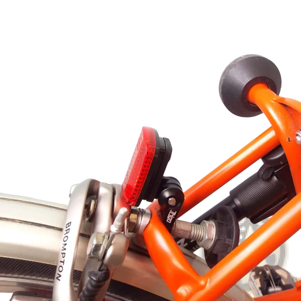 Red rectangular rear bike light mounted on orange brompton frame shown from the back on trigo brompton camera mount bracket