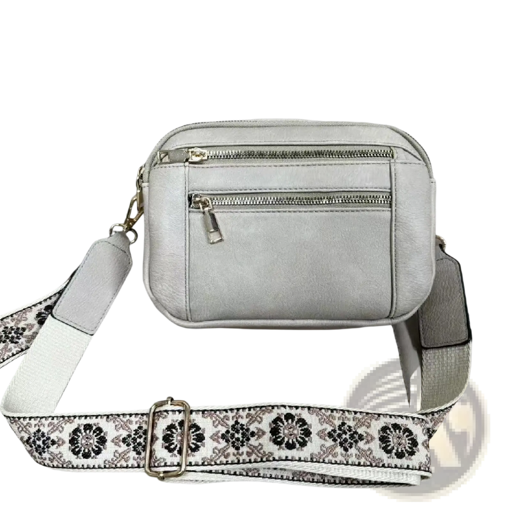 Light gray faux leather crossbody bag with triple zippers and a decorative floral colorblock strap